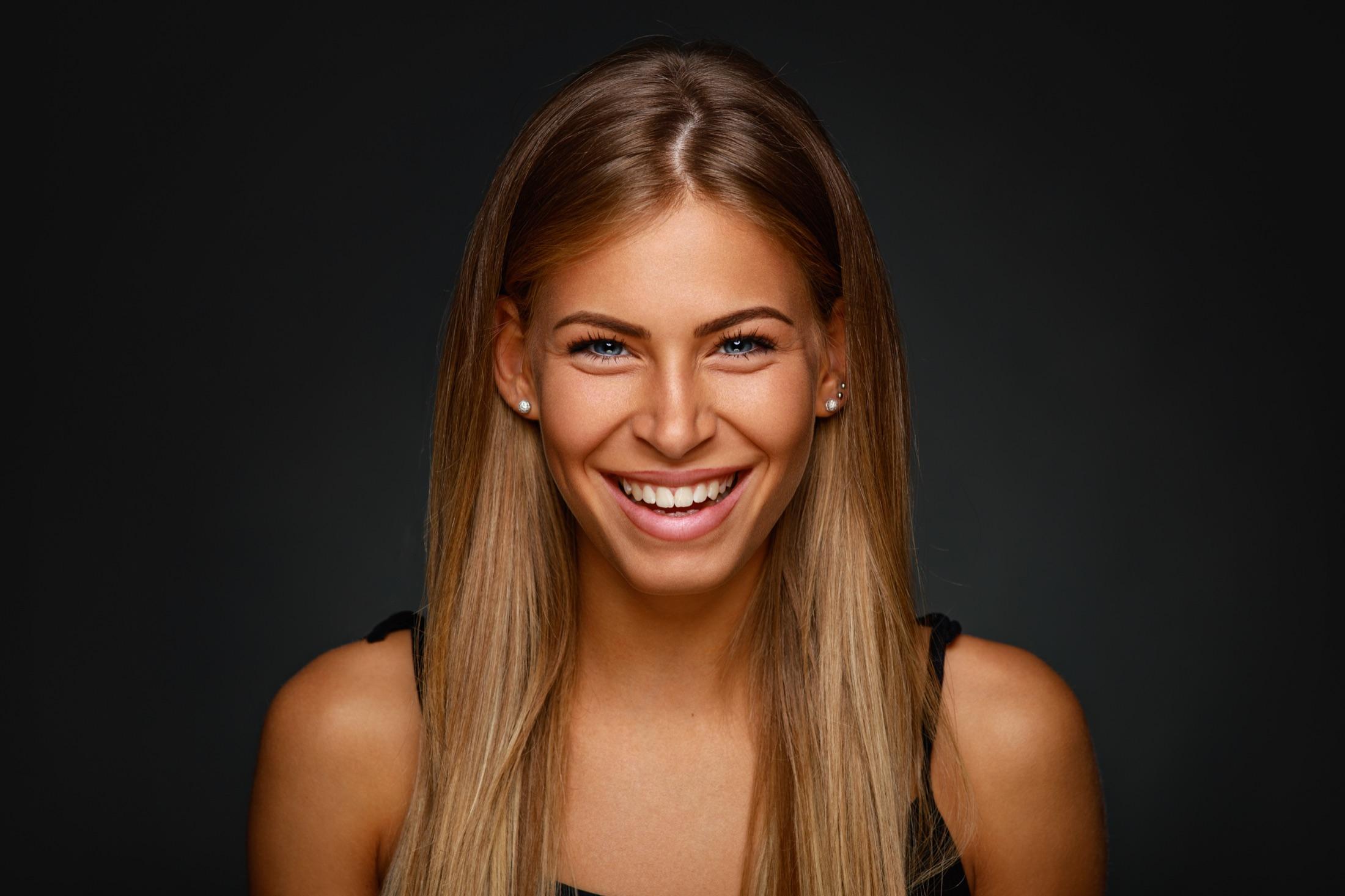 A smiling client portrait against a dark background, satisfied after approving her emerald order
