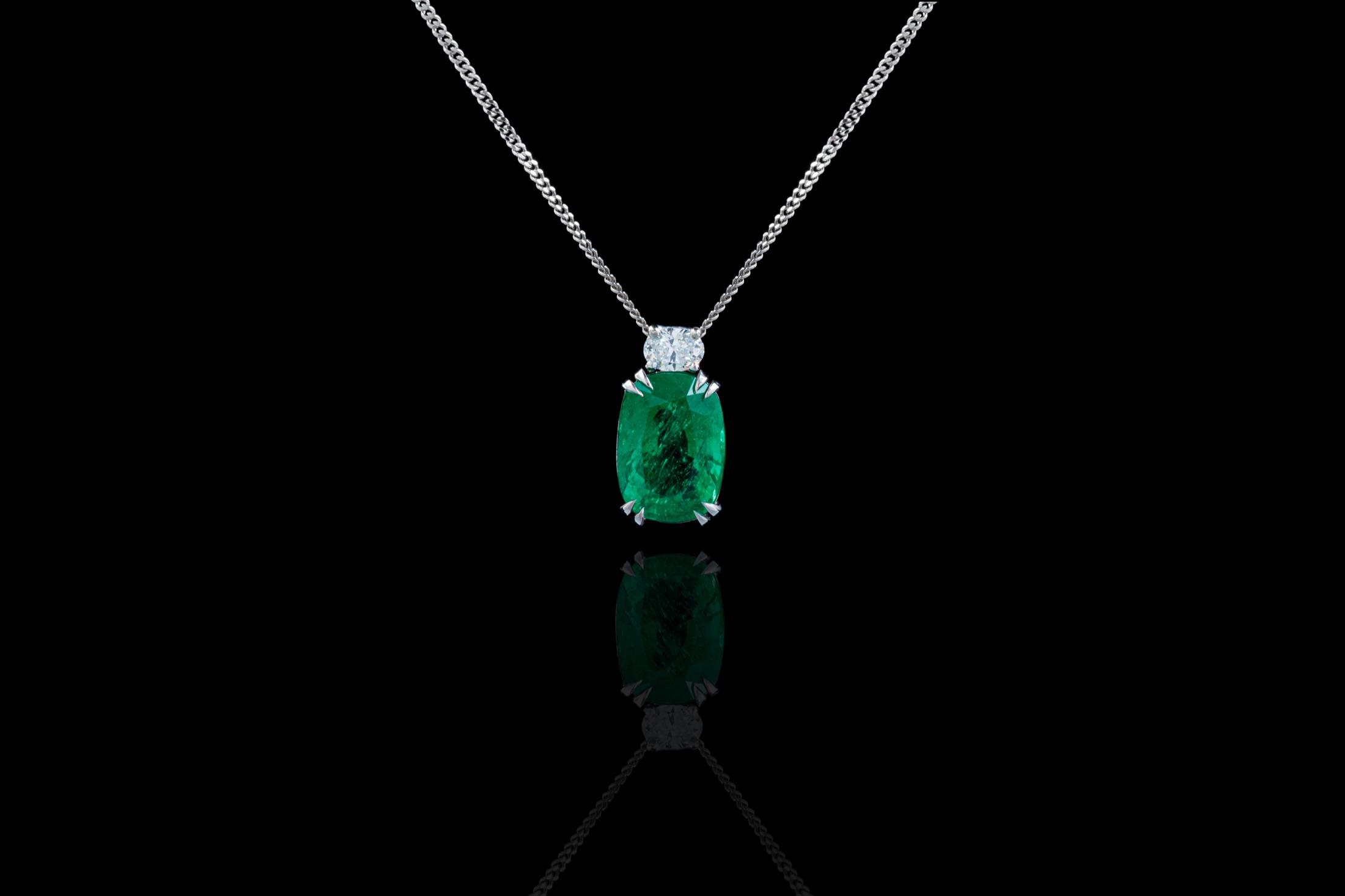 Emerald pendant necklace on a reflective dark surface