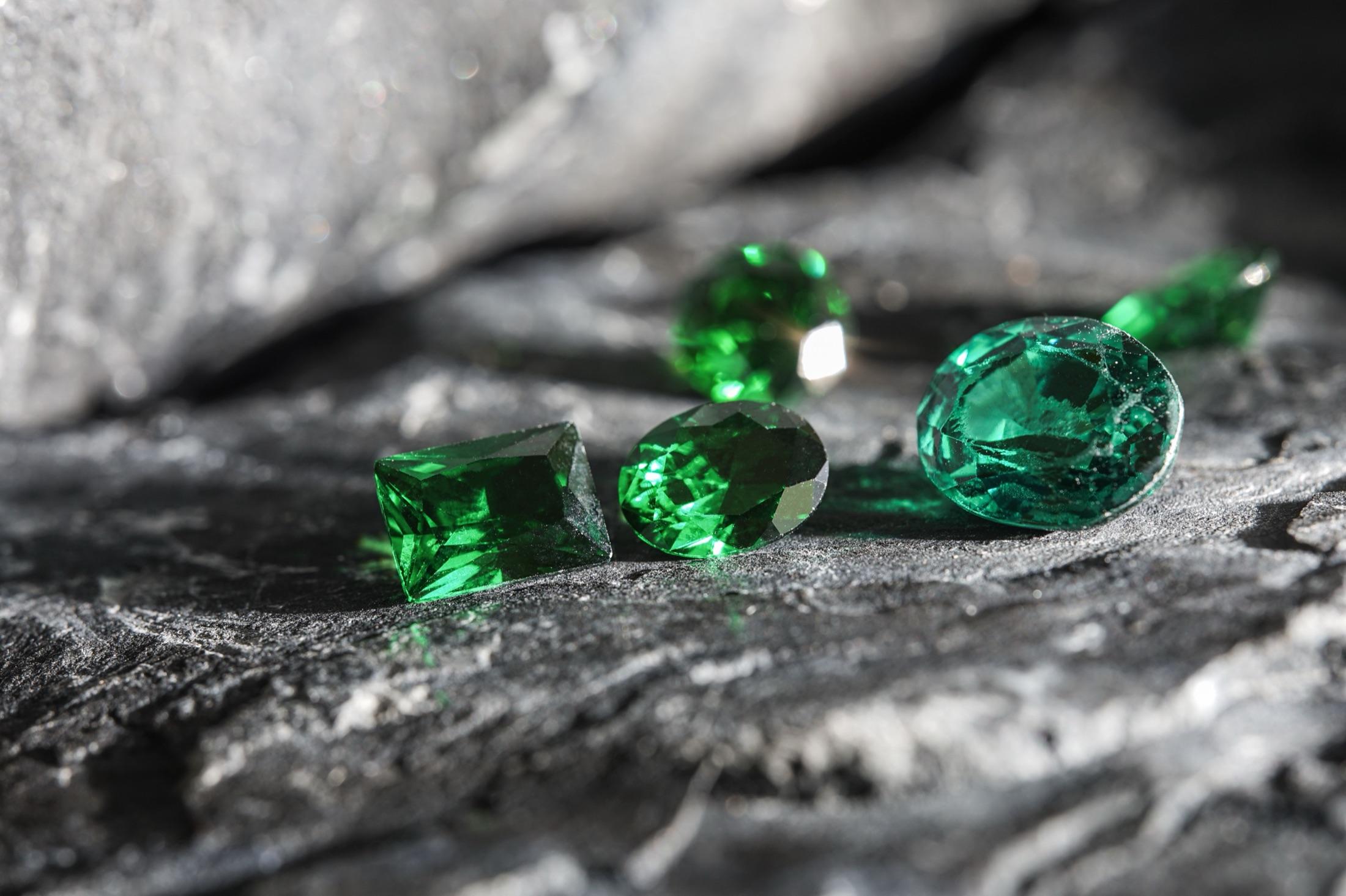 Several cut Colombian emeralds gathered on natural rock